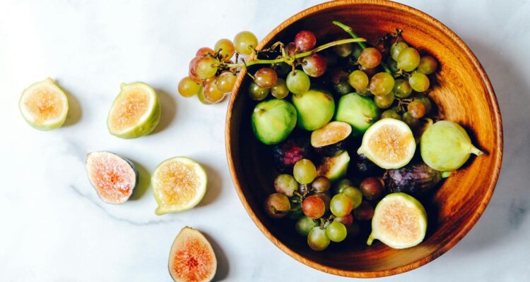 A vibrant and fresh bowl of green grapes and figs on a marble surface, perfect for healthy eating.