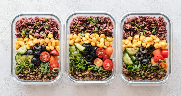 Colorful healthy meal prep with corn, olives, tomatoes, and lentils in glass containers. Perfect for mindful eating.